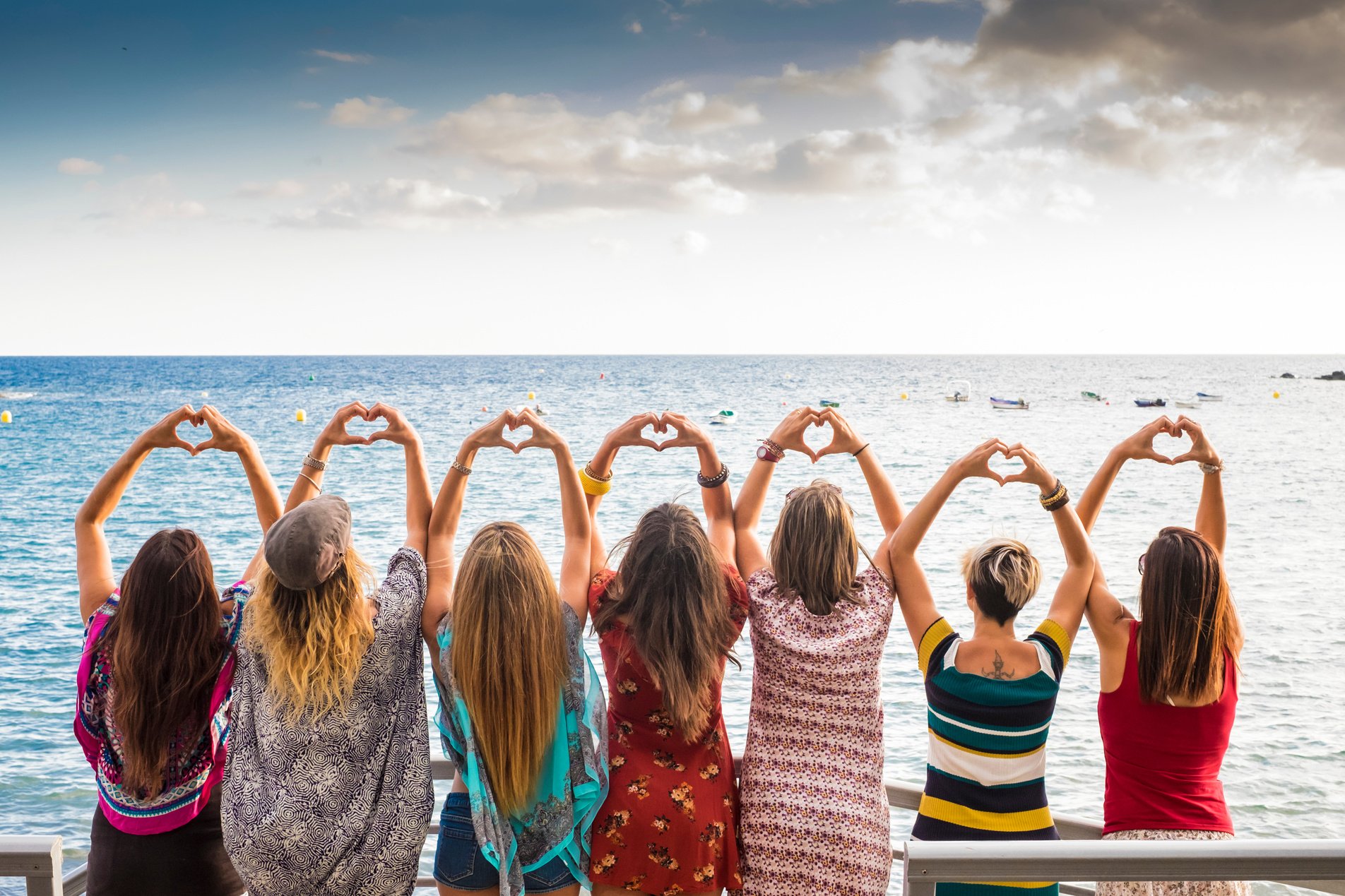 Back View of Female Friends with Hands Showing Heart Gesture